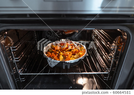 Baked potatoes with carrot and other spices in roasting pan. 60664581