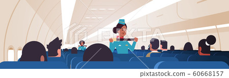 stewardess explaining passengers how to use seat belt fastening in emergency situation african american flight attendants in uniform safety demonstration concept airplane board interior horizontal 60668157
