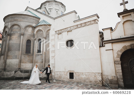A loving wedding couple are walking back along the streets of the city of Lviv 60669228
