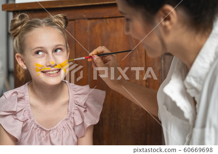 Caucasian lady painting face of little girl indoors Caucasian lady painting face of little girl indoors 60669698