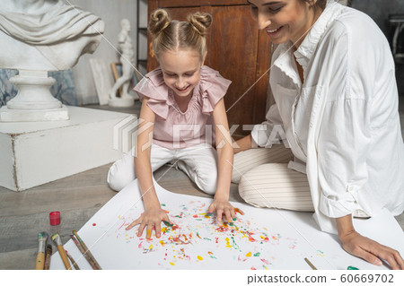 Funny little girl making picture with painted coloured palms Funny little girl making picture with painted coloured palms 60669702