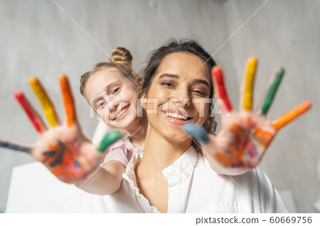 Small pretty daughter with painted palms having fun with her mother 60669756