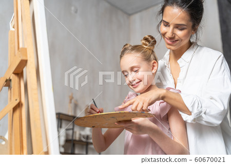 Caucasian happy female artist teaching cute girl to paint 60670021