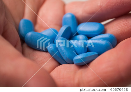 Closeup of blue pils in hand on white background 60670428