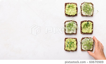 Girl taking vegan toasts with avocado, tofu and microgreens Girl taking vegan toasts with avocado, tofu and microgreens 60670989