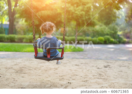 Unrecognizable Little Caucasian girl riding swing Unrecognizable Little Caucasian girl riding swing 60671365