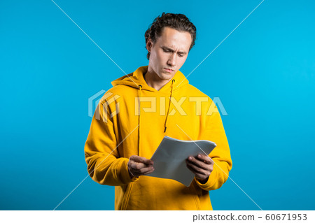 Serious businessman boss on blue background. He is anxious and confused with work of staff. Young male office employee checks documents, reports Serious businessman boss on blue background. He is anxious and confused with work of staff. Young male office employee checks documents, reports 60671953