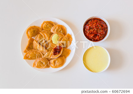 Traditional russian and ukrainian food vareniki dumplings with mustard and tomato sauce on a white plate. 60672694