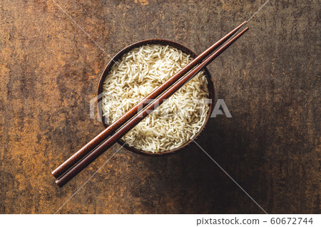 Uncooked indian long rice in bowl and chopsticks. 60672744