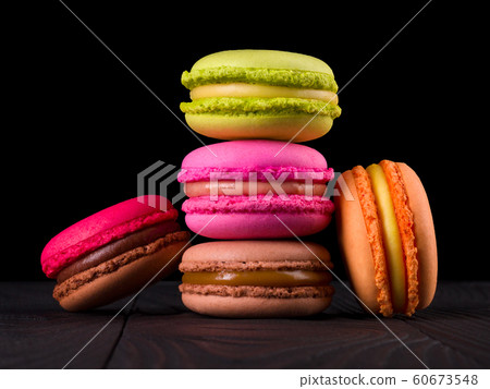 Heap of french colorful macaroons on wooden table isolated on black Heap of french colorful macaroons on wooden table isolated on black 60673548
