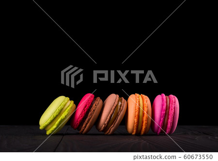 French colorful macaroons in row on wooden table isolated on black French colorful macaroons in row on wooden table isolated on black 60673550