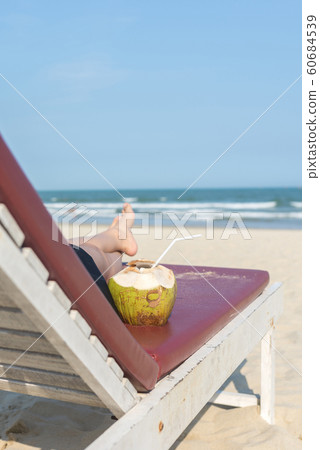 Rear view of woman on summer beach chair with coconut Rear view of woman on summer beach chair with coconut 60684539