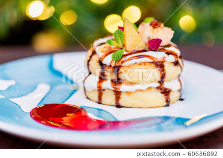 Cottage cheese pancakes or syrniki with cream, fruit jam and flower decoration 60686892