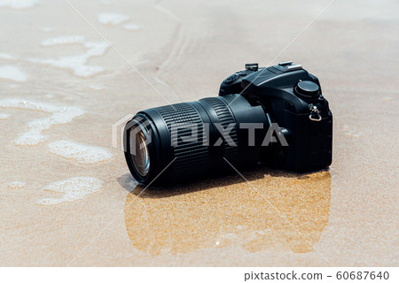 DSLR camera on beach wet from water sea wave DSLR camera on beach wet from water sea wave 60687640