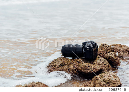 DSLR camera on stone beach wet from water sea wave 60687646