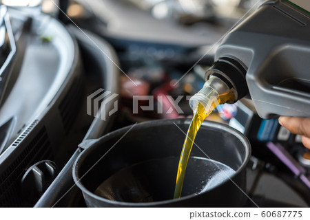 Car mechanic fills a fresh lubricant engine oil Car mechanic fills a fresh lubricant engine oil 60687775