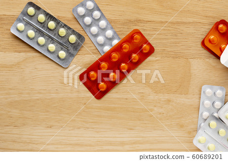 Different blister pack with round pills on a wooden table Different blister pack with round pills on a wooden table 60689201