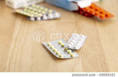 Different blisters with tablets on a wooden table Different blisters with tablets on a wooden table 60689281