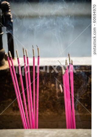 Incense sticks burning inside brass pot in a 60694970