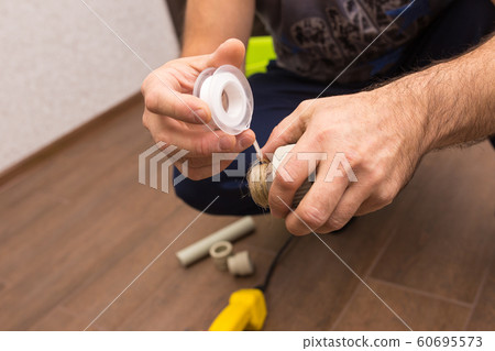 Preparing to connect the water supply. Winding the tape. Hands plumbing close-up. 60695573