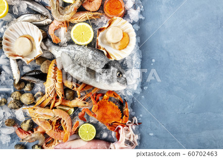 Fish and seafood variety, a flat lay overhead shot with a place for text. Fresh fish, shrimps, crab, squid, mussels and clams, scallops and caviar, shot from the top on ice 60702463