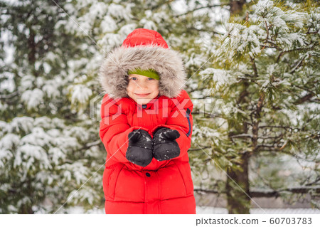 Happy boy plays with snow. Cute kid throwing snow in a winter park. Happy winter holidays. Winter 60703783