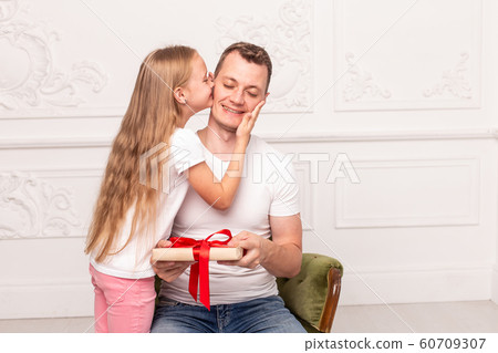 Little girl kiss her father, who hold giftbox in hand, in cheek. Selective focus 60709307