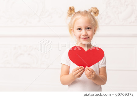Little adorable girl holds little red heart made of papper in hands Little adorable girl holds little red heart made of papper in hands 60709372