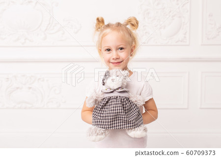 Little blond cheerful girl holds toy bear in hands and smile 60709373