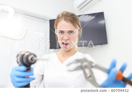 Woman dentist in white uniform holds builder instruments in hands. Selective focus 60709432