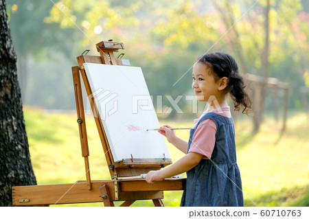 Lovely little girl show happy smile and enjoy with painting in the garden 60710763