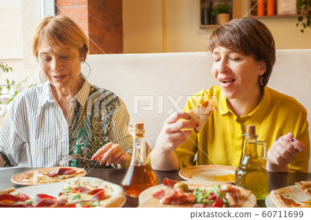 Two happy mature women eating and chatting in 60711699