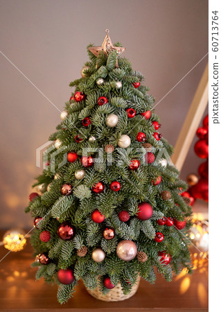 Beautiful small Christmas tree on wooden table. Happy mood. Garland lamp bokeh on background. Wallpaper. Danish pine and fir, Nobilis Beautiful small Christmas tree on wooden table. Happy mood. Garland lamp bokeh on background. Wallpaper. Danish pine and fir, Nobilis 60713764