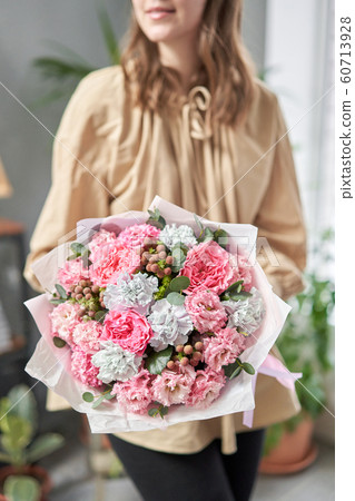 European floral shop. Beautiful bouquet of mixed flowers in womans hands. the work of the florist at a flower shop. Delivery fresh cut flower. 60713928