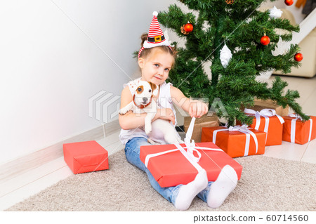 Kid opening Xmas presents. Child under Christmas tree with gift boxes. 60714560