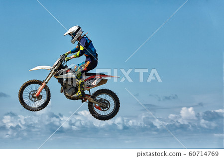 Extreme sports, motorcycle jumping. Motorcyclist makes an extreme jump against the sky. Film grain effect, illumination 60714769