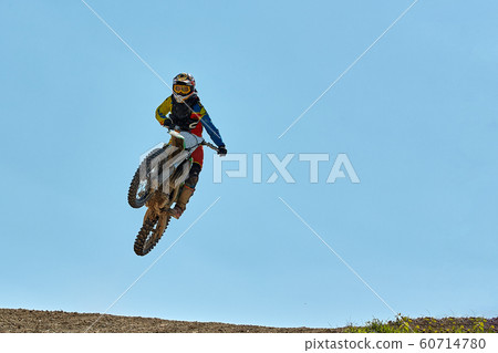 Extreme sports, motorcycle jumping. Motorcyclist makes an extreme jump against the sky. Film grain effect, illumination 60714780