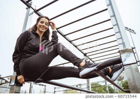 Positive delighted female person sitting on sports equipment 60715544