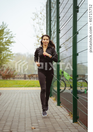 Positive delighted young woman running in the yard 60715752
