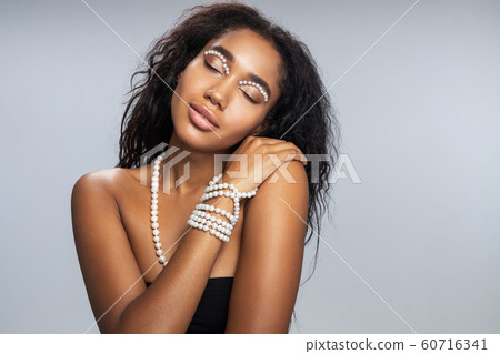 Relaxed woman with startling makeup posing for camera Relaxed woman with startling makeup posing for camera 60716341