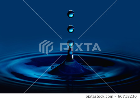 Water drop splash in a glass cup blue colored Water drop splash in a glass cup blue colored 60718230