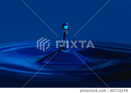 Water drop splash in a glass cup blue colored Water drop splash in a glass cup blue colored 60718249