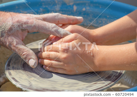 Hands of potter and child work with clay Hands of potter and child work with clay 60720494