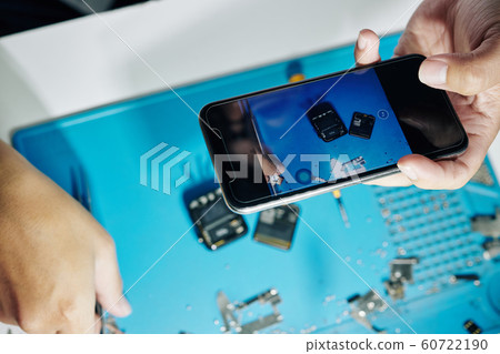 Repairman photographing disassembled smartwatch Repairman photographing disassembled smartwatch 60722190