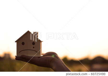Closeup hand holding mockup house wood with face 60725490