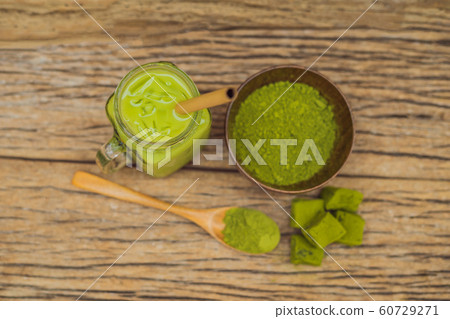 Green tea latte with ice in mason jar, matcha powder and candy made of matcha on wooden background. Homemade Iced Matcha Latte Tea with Milk zero waste Green tea latte with ice in mason jar, matcha powder and candy made of matcha on wooden background. Homemade Iced Matcha Latte Tea with Milk zero waste 60729271