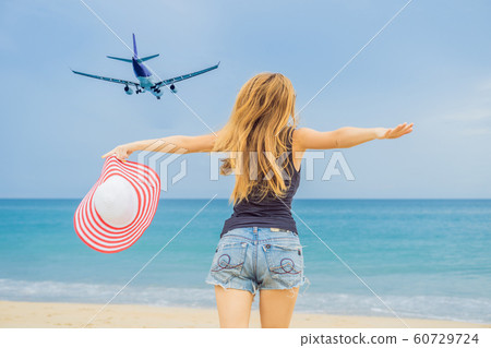Woman have fun on the beach watching the landing planes. Traveling on an airplane concept Woman have fun on the beach watching the landing planes. Traveling on an airplane concept 60729724