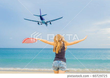 Woman have fun on the beach watching the landing planes. Traveling on an airplane concept Woman have fun on the beach watching the landing planes. Traveling on an airplane concept 60729725