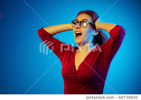 Caucasian woman's portrait isolated on blue studio background in neon light Caucasian woman's portrait isolated on blue studio background in neon light 60730020