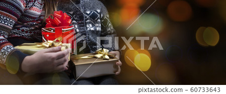 Children's hands are holding a gifts boxes for Christmas or a New Year on the colorful bokhe background. Close Up 60733643